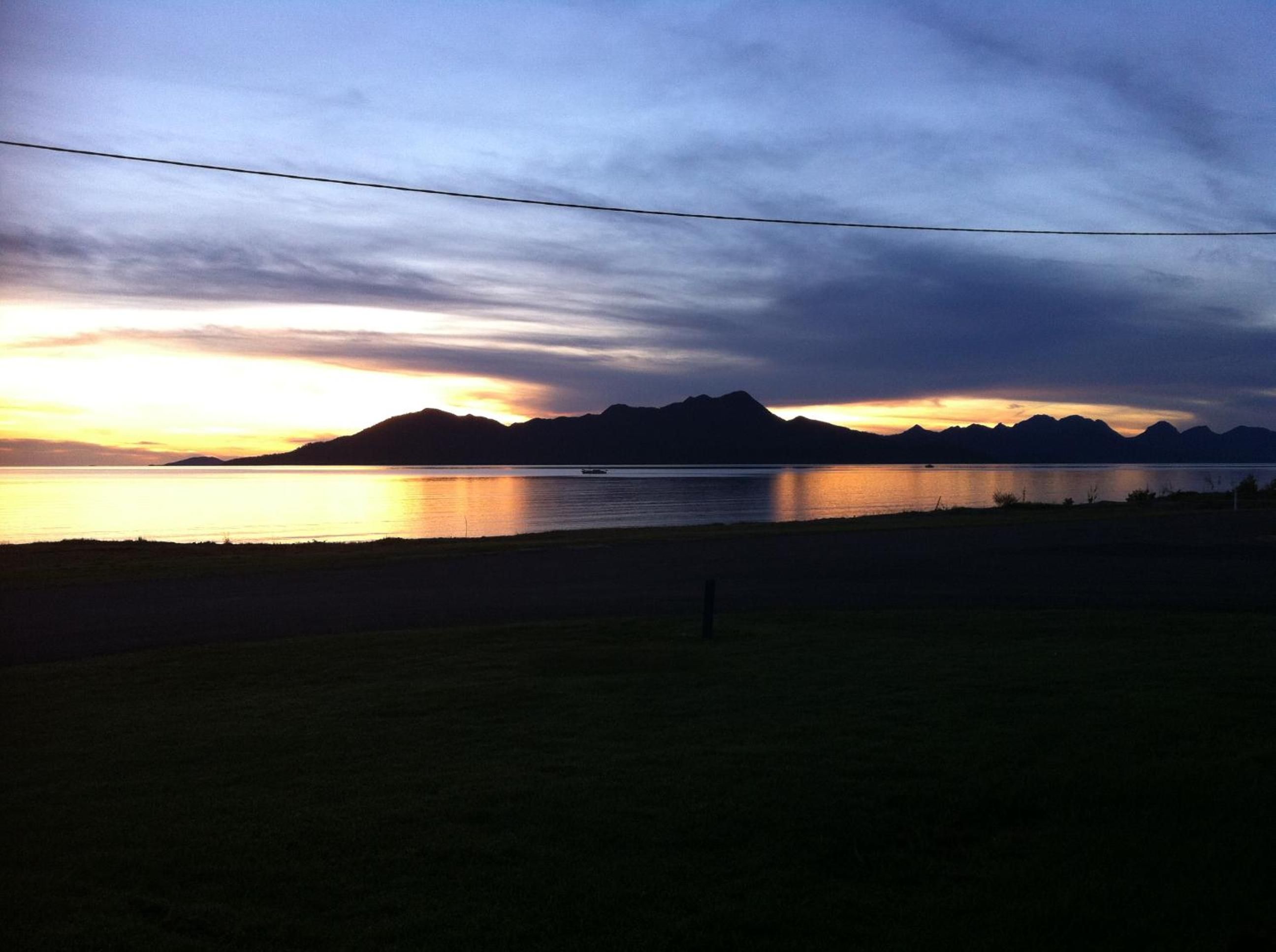 A serene landscape with a body of water, mountains in the distance, and a clear sky.