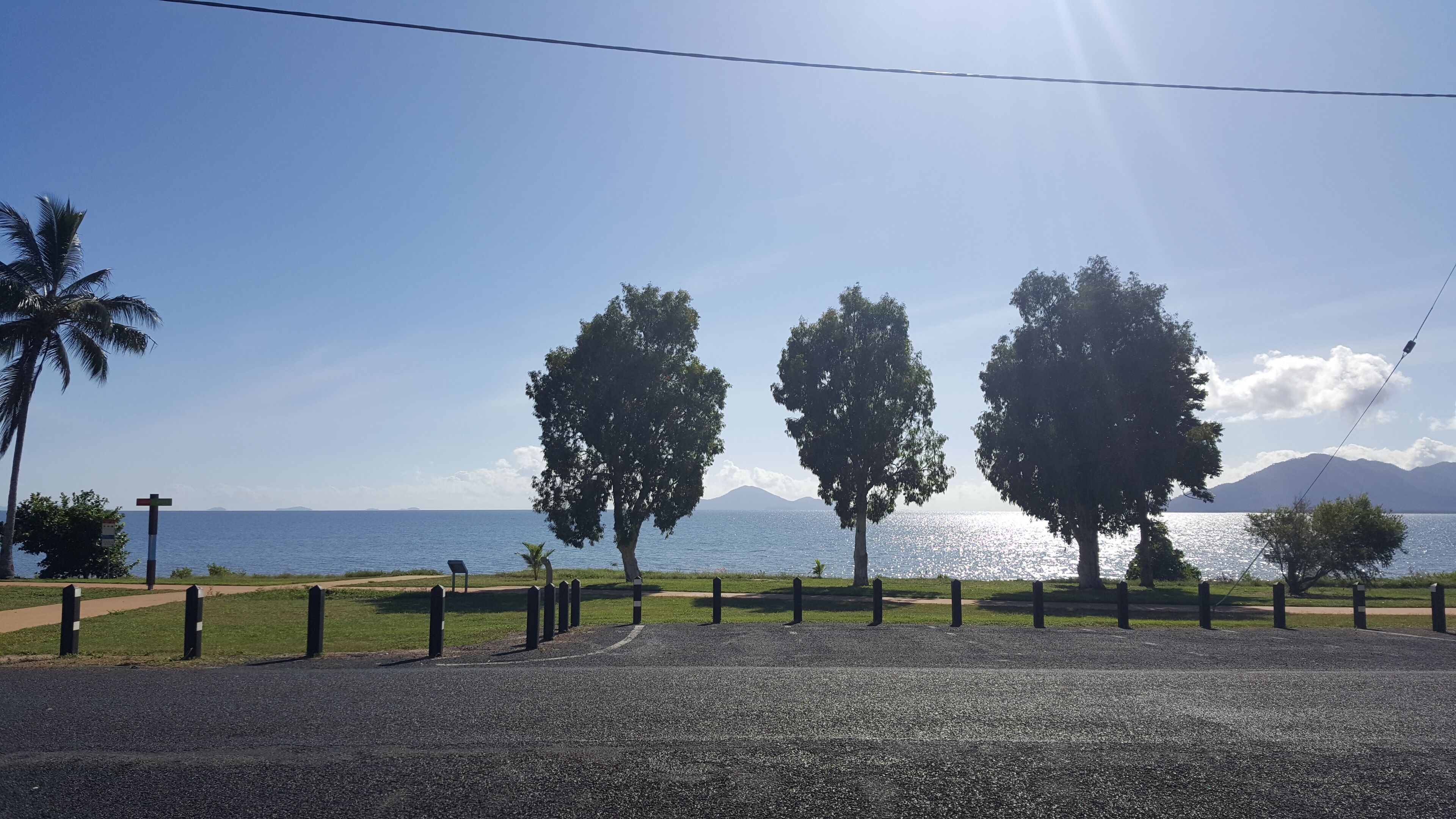A paved area with trees and a view of the sea.