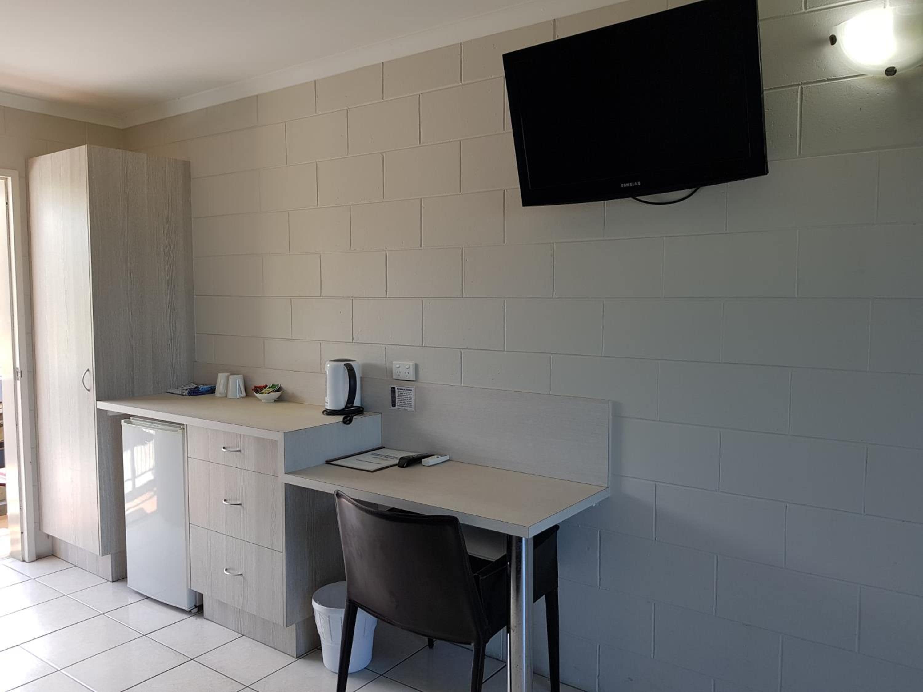 A kitchenette with a built-in oven, a coffee maker, and a flat-screen TV mounted on the wall.