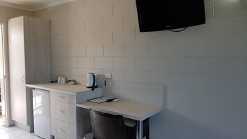 A kitchenette with a built-in oven, a coffee maker, and a flat-screen TV mounted on the wall.