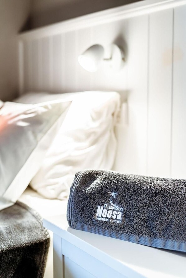 A neatly made bed with a white pillow and a black towel with text on it.