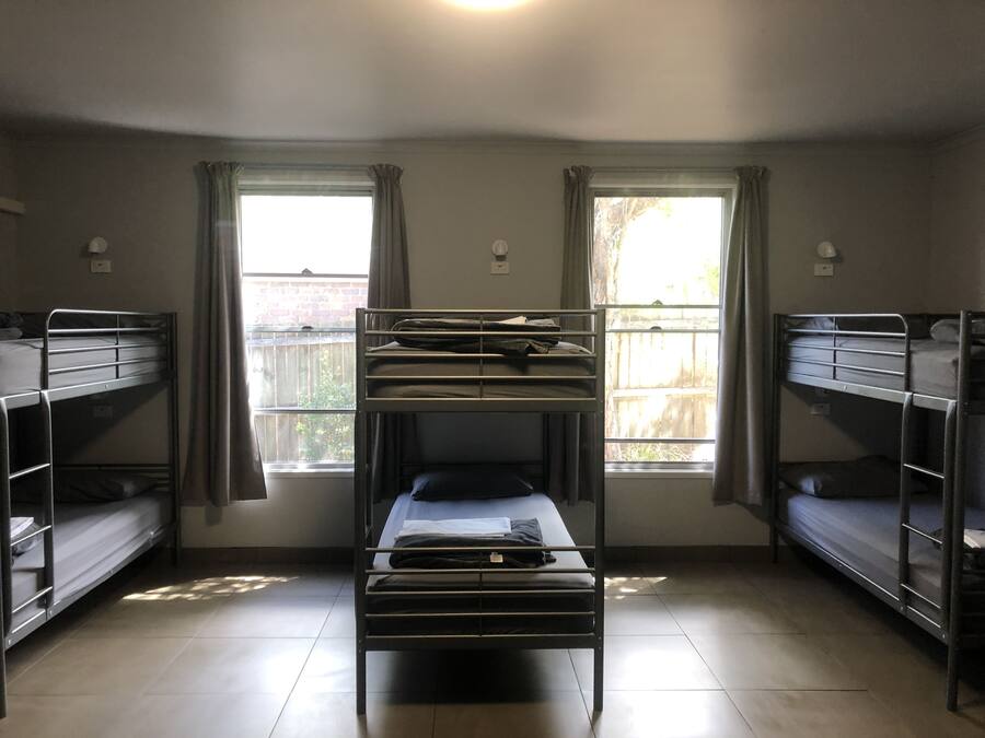 Un dormitorio con literas, dos ventanas con cortinas y un escritorio pequeño.