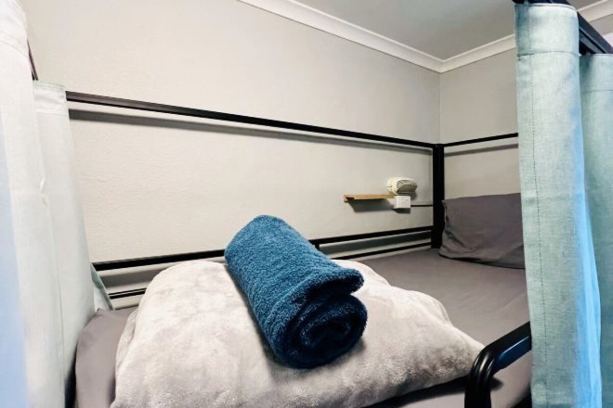 A bunk bed with a rolled-up blue towel on the lower bunk and a white pillow.