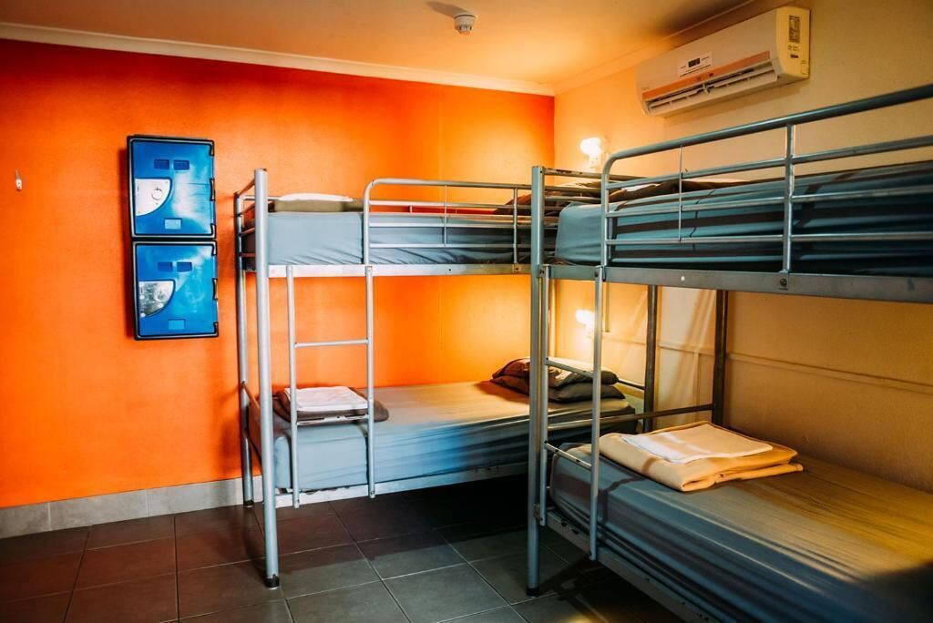 A bunk room with two bunk beds, a ladder, and a wall-mounted air conditioning unit.