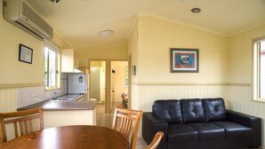 Un espacio habitable compacto con cocina, comedor y un sofá de cuero negro.