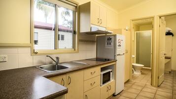 Cocina compacta con pileta, microondas y refrigerador, además de un ventanal visible.