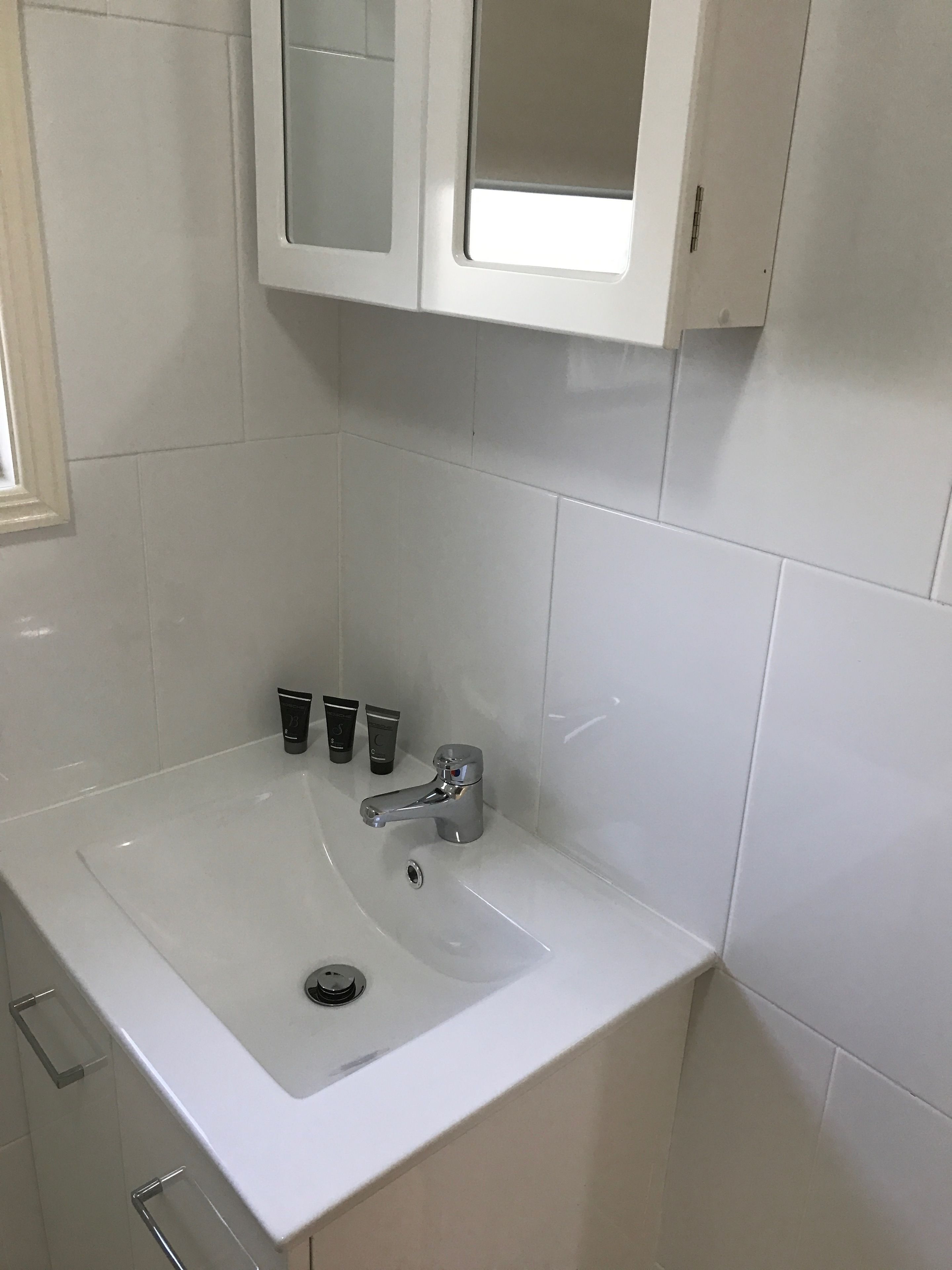 A bathroom with a white sink, a mirror, and a cabinet above it.