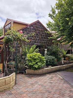 A stone building with a garden in front, including a statue and various plants. - The Camperdown Mill - South West Victoria (Camperdown)