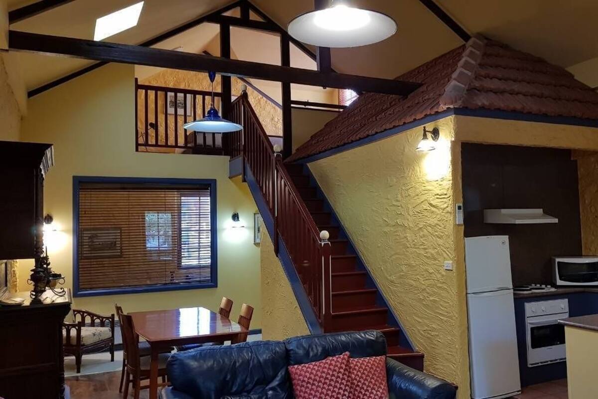 A compact kitchen with a dining area, a staircase, and a living room with a sofa and a table.