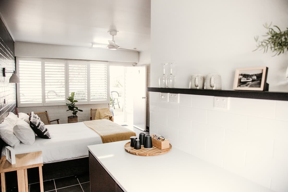 A modern bedroom with a bed, bedside table, and a view of the outside.