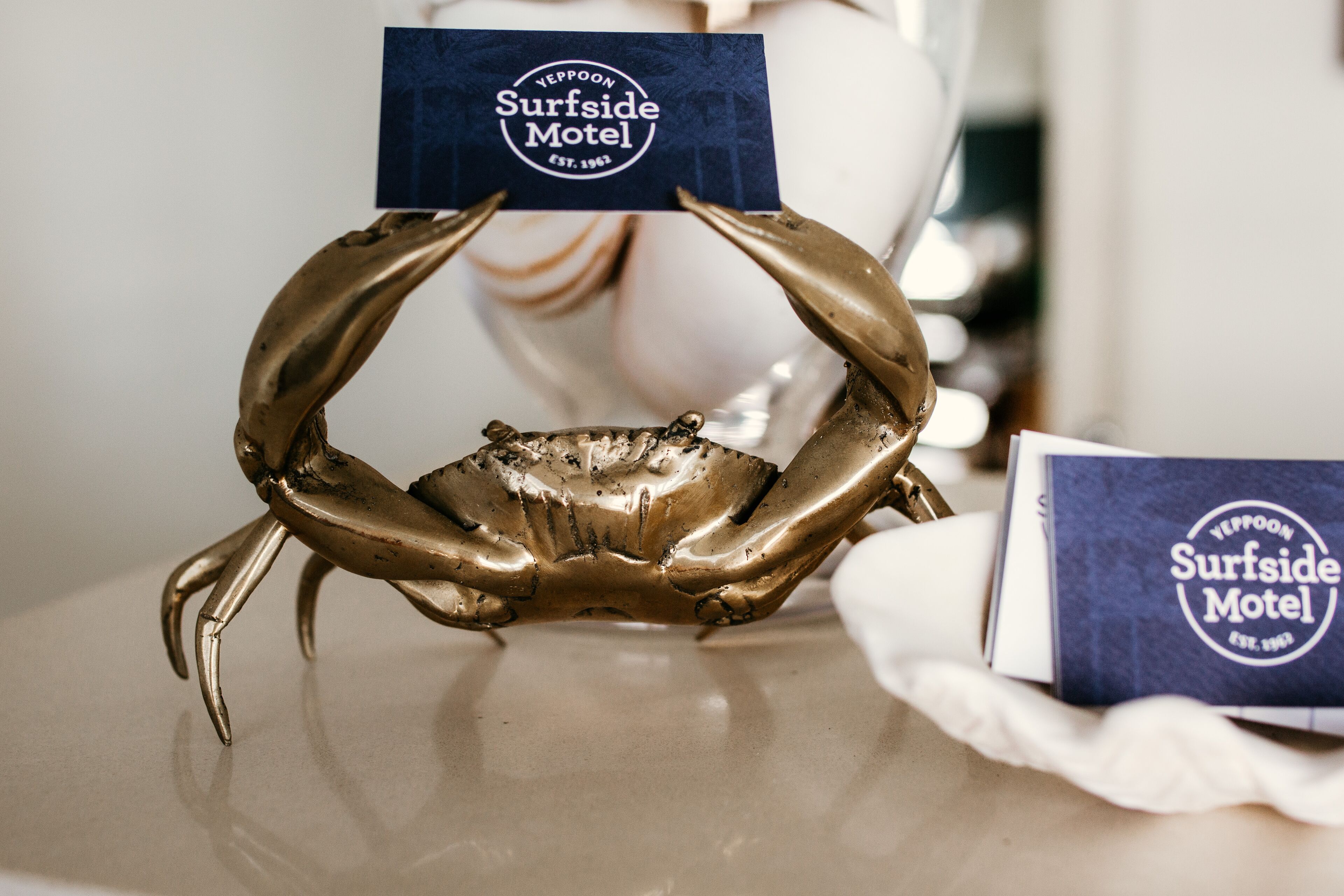 A gold crab sculpture with a business card labeled "Surfside Motel" on a table.