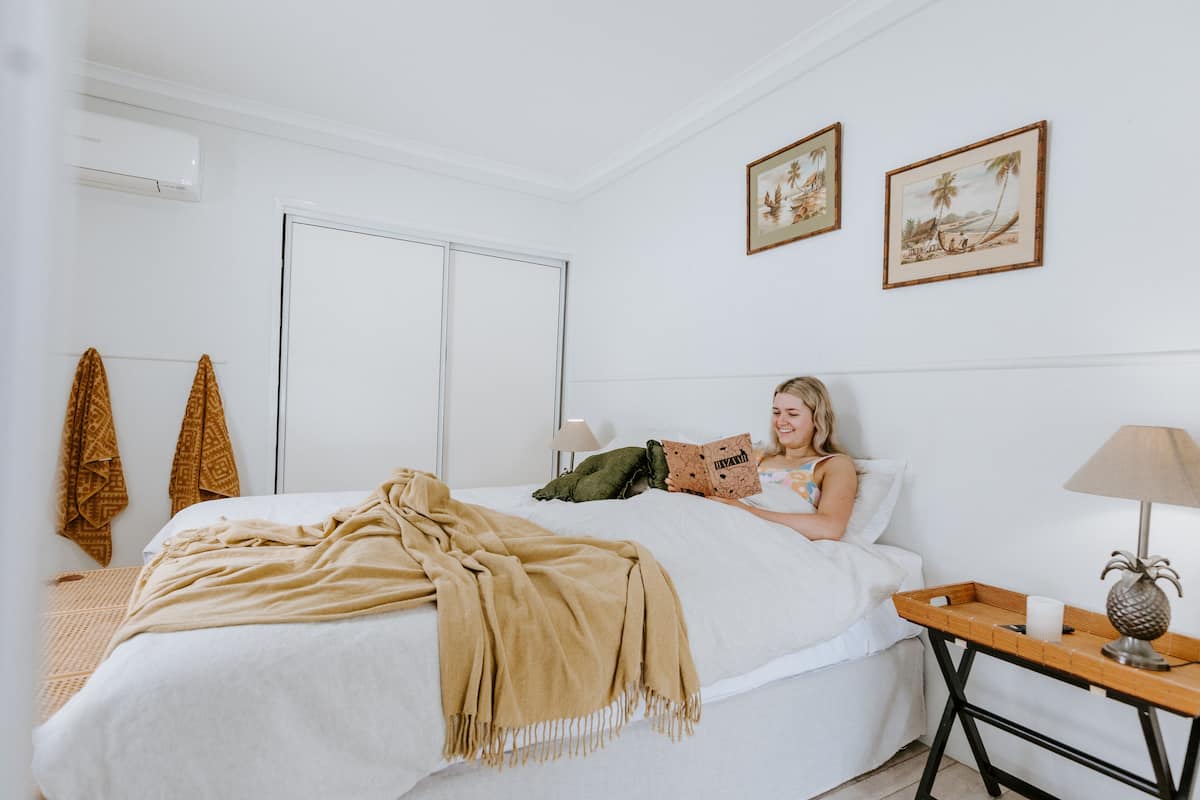 A bedroom with a bed, a bedside table with a lamp, and two framed pictures on the wall.