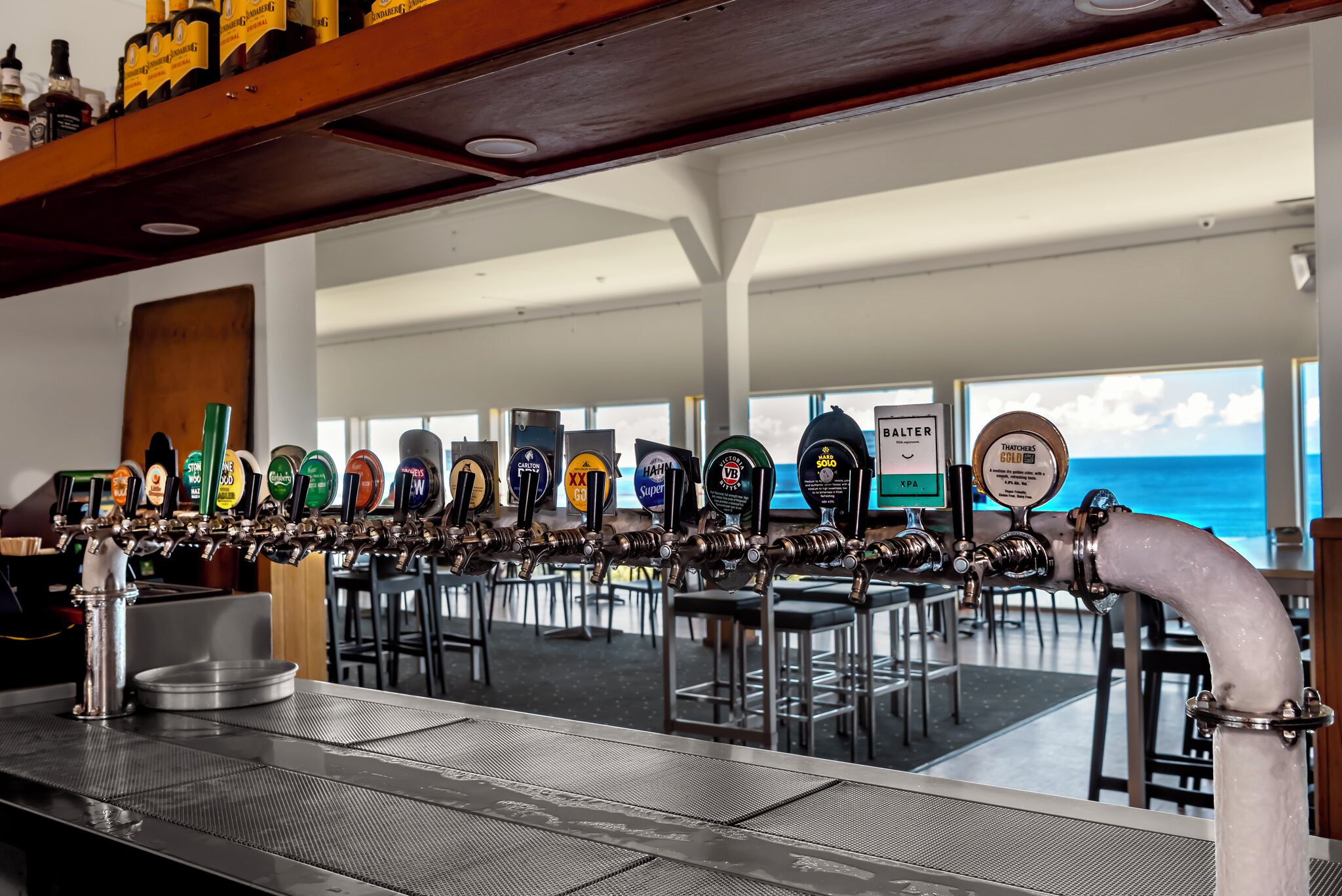 A bar with a beer tap system and a view of the ocean.