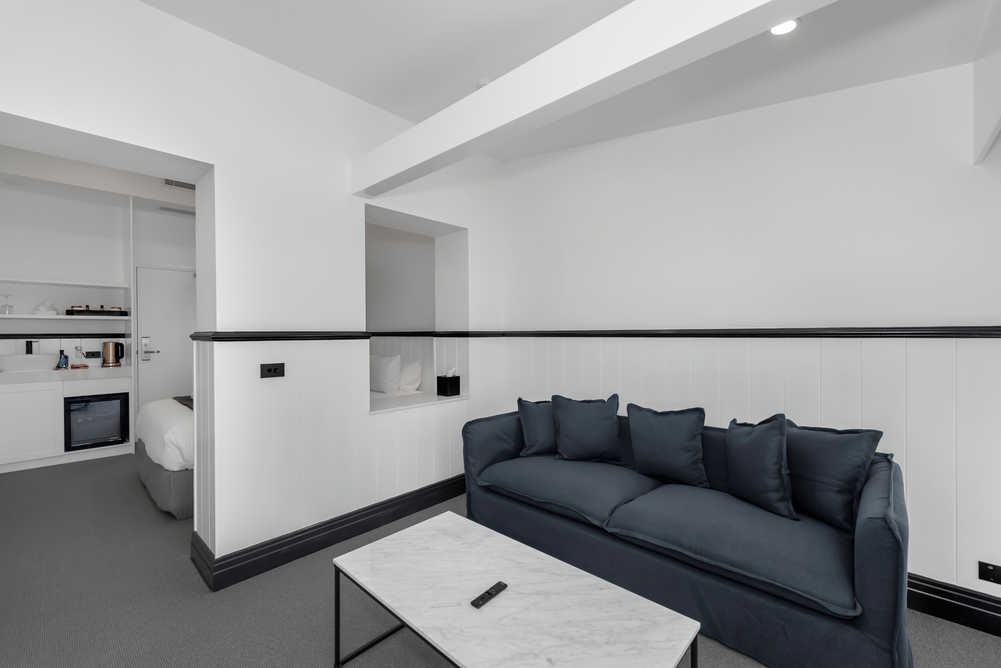 A modern living room with a grey sofa, a white coffee table, and a built-in shelving unit.