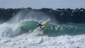 Un surfista montando una ola, con una costa rocosa al fondo.