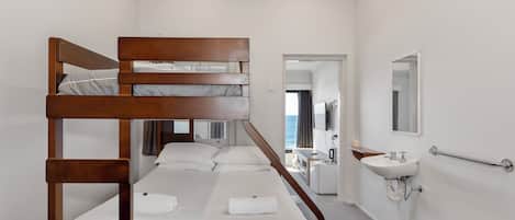 Quarto com beliches e banheiro, incluindo pia e espelho.