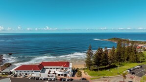 A coastal hotel with a red-roofed building, parking area, and ocean view. - Pacific Hotel Yamba (Yamba)