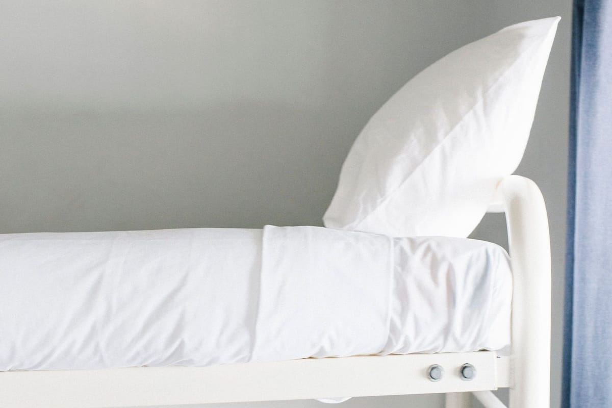 A bunk bed with white bedding and a pillow.