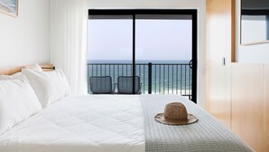 A hotel room with a bed, a balcony with a view of the sea, and two chairs. - Pacific Hotel Yamba (Yamba)