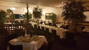 A restaurant with tables set for dining, potted plants, and a warm ambiance. - Kerang Valley Resort (Kerang)