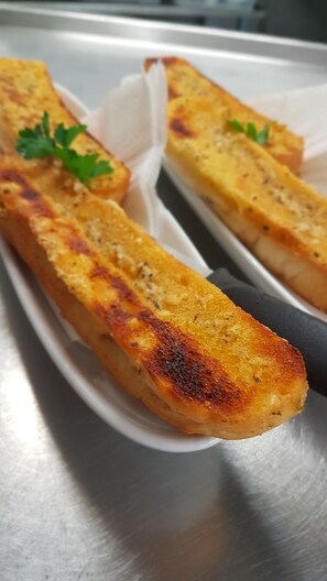 A close-up of grilled cheese sandwiches with a golden-brown crust, garnished with parsley, on a white plate. - Kerang Valley Resort (Kerang)