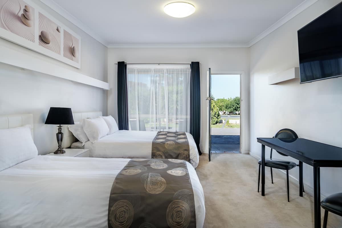 Habitación de hotel con dos camas, un escritorio y una televisión.