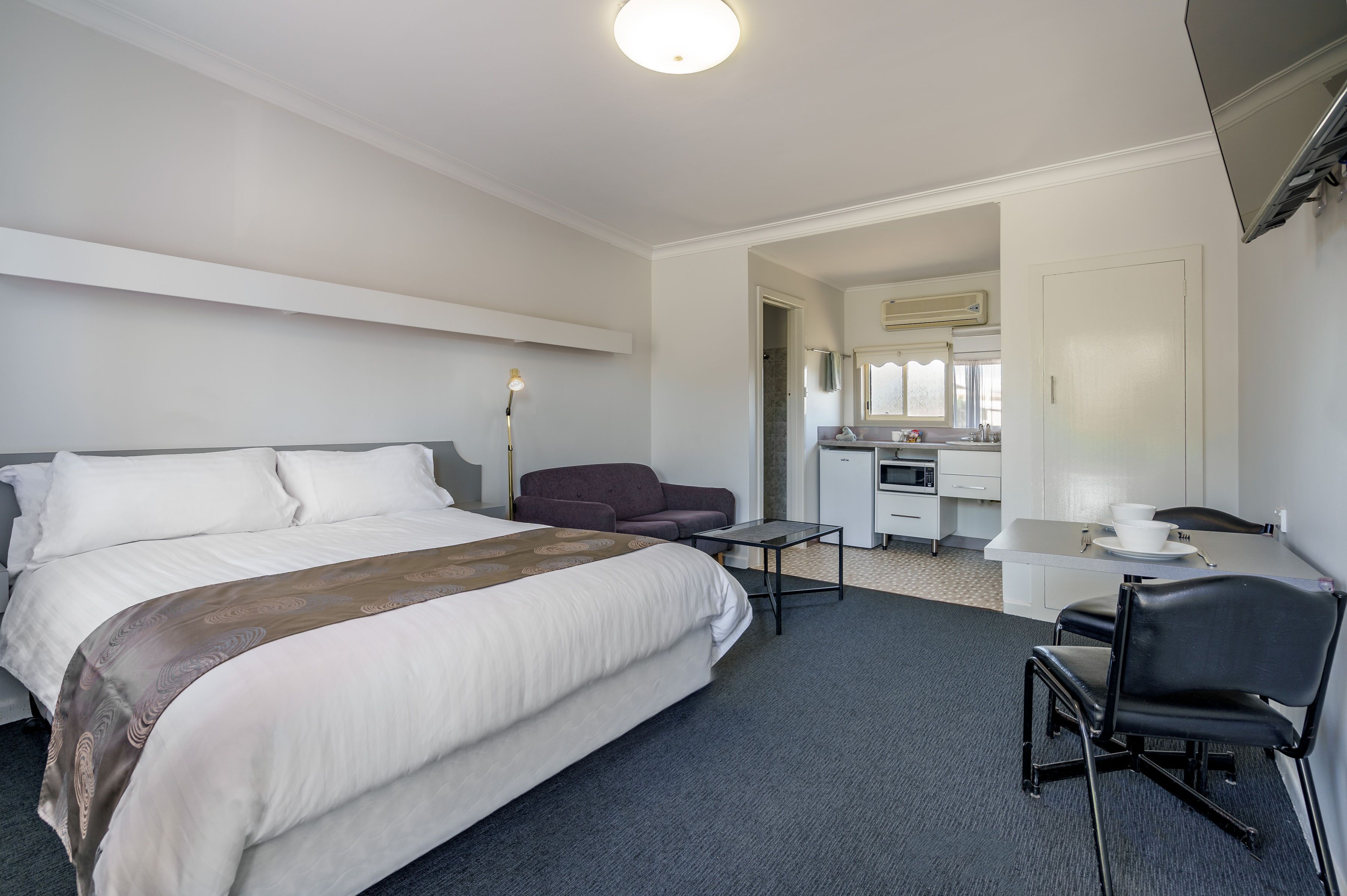 A hotel room with a large bed, a desk, a chair, and a sofa.
