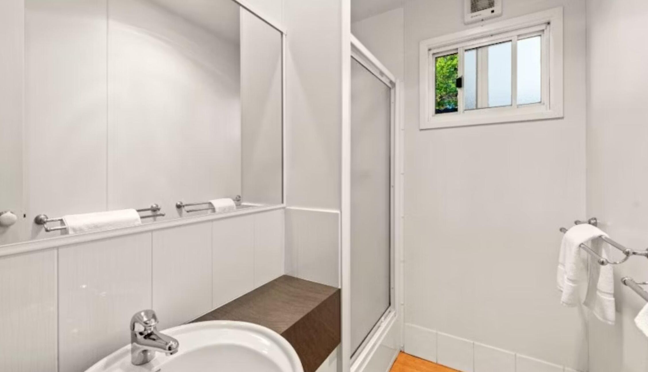 Une salle de bain moderne avec un lavabo, un miroir et un porte-serviettes.
