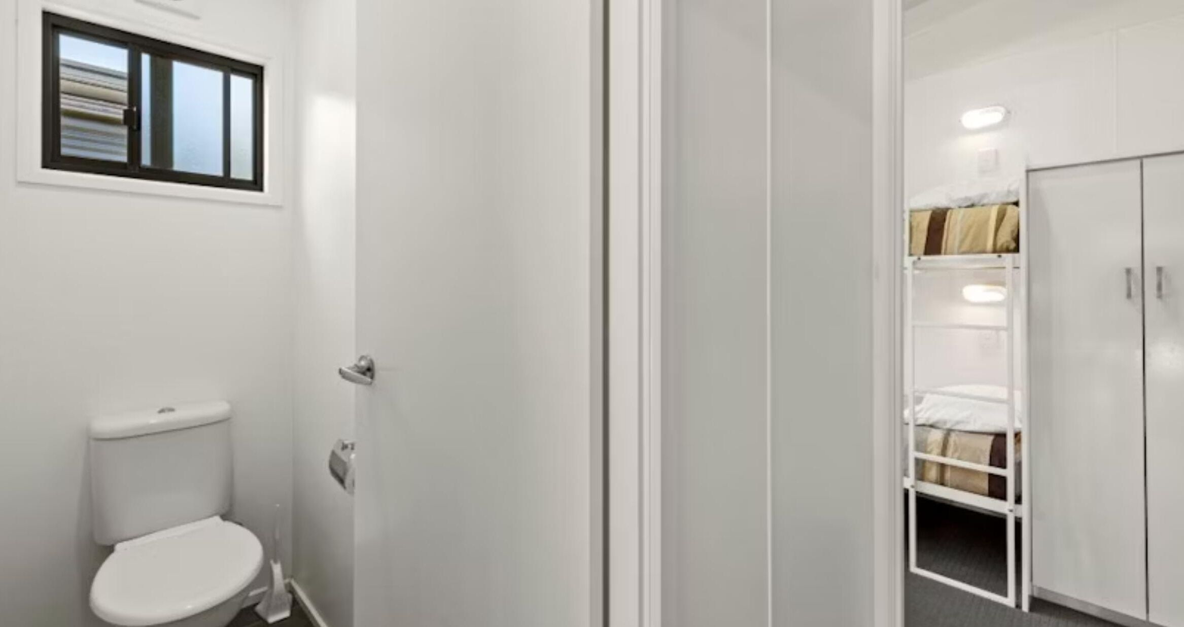 Ein Badezimmer mit Toilette, Duschbereich und einem Kleiderschrank mit Platz zum Aufhängen.