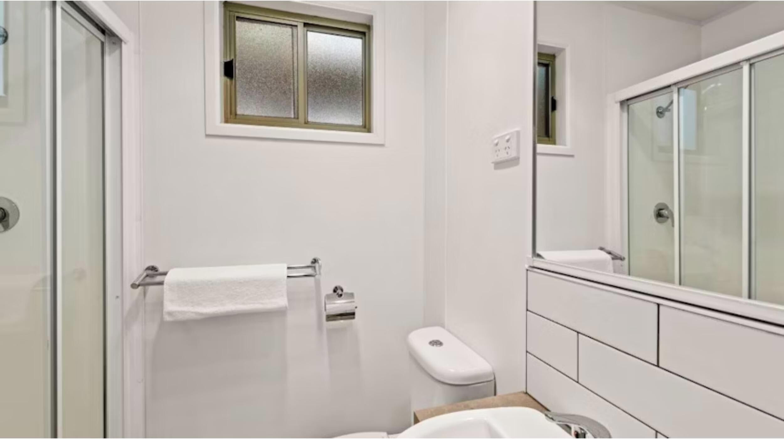 Un baño moderno con cabina de ducha de vidrio, inodoro y lavamanos.