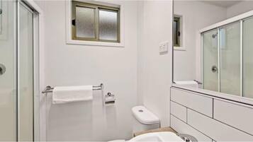 Un baño moderno con cabina de ducha de vidrio, inodoro y lavamanos.
