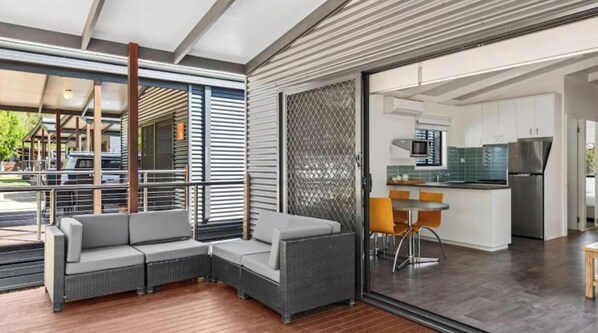 A modern interior with a sectional sofa, a dining area, and a kitchen. - Discovery Parks - Mount Buffalo (Porepunkah)
