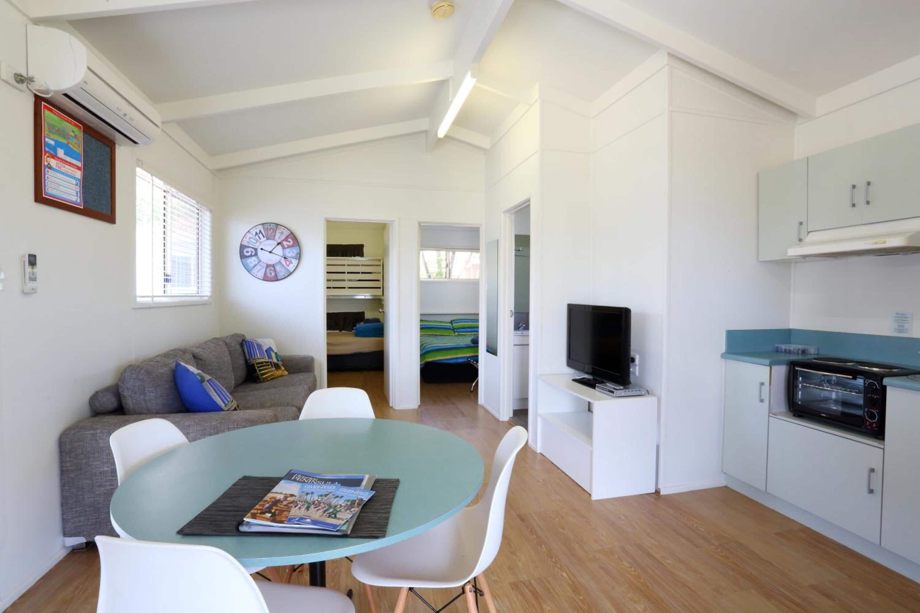 A compact living space with a kitchenette, a dining area, and a bedroom.