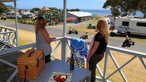 A covered outdoor area with picnic tables, a wicker basket, and a bottle of wine. - Brighton Beachfront Holiday Park (Kingston Park)
