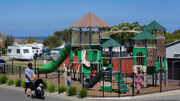 A playground with a slide and climbing structures, surrounded by a fence. - Brighton Beachfront Holiday Park (Kingston Park)