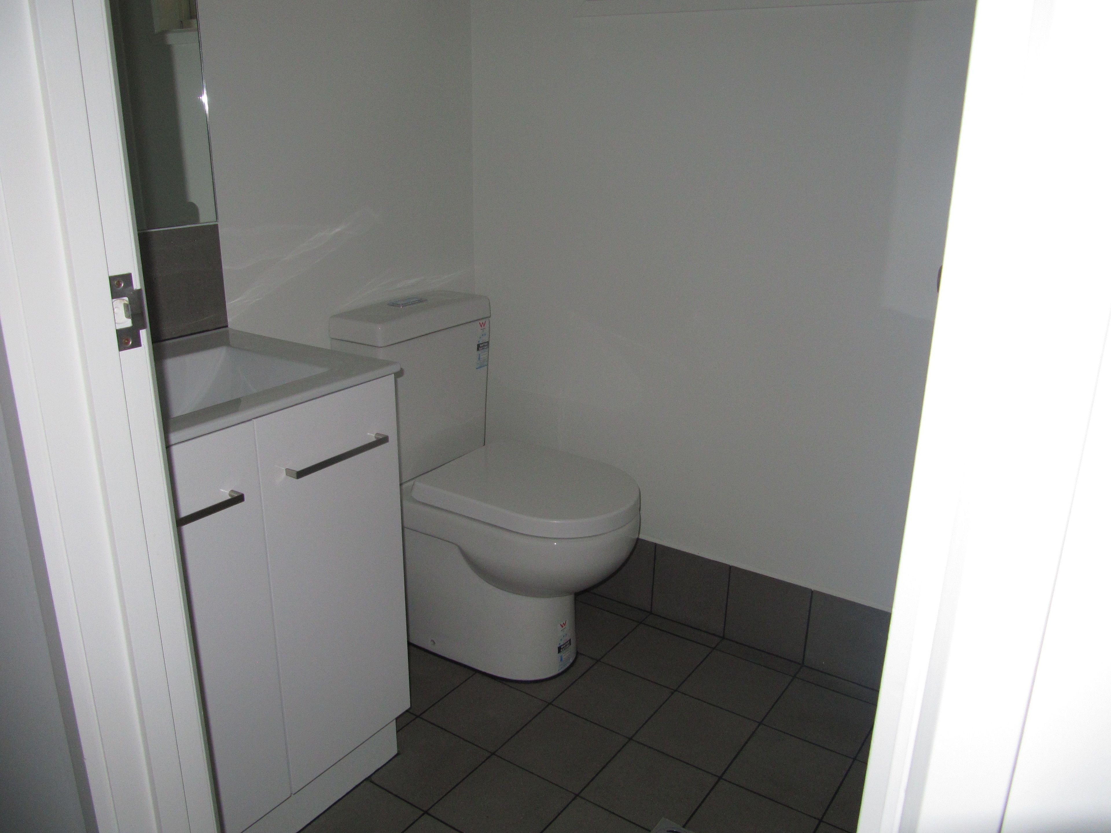 A small, clean bathroom with a toilet, a sink, and a cabinet.