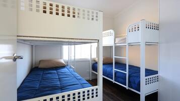 A dormitory room with bunk beds, a window, and a door.