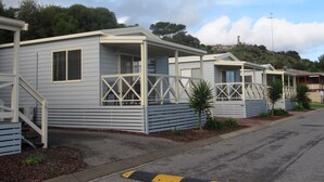 A row of mobile homes with attached porches and a small hill in the background. - Brighton Beachfront Holiday Park (Kingston Park)