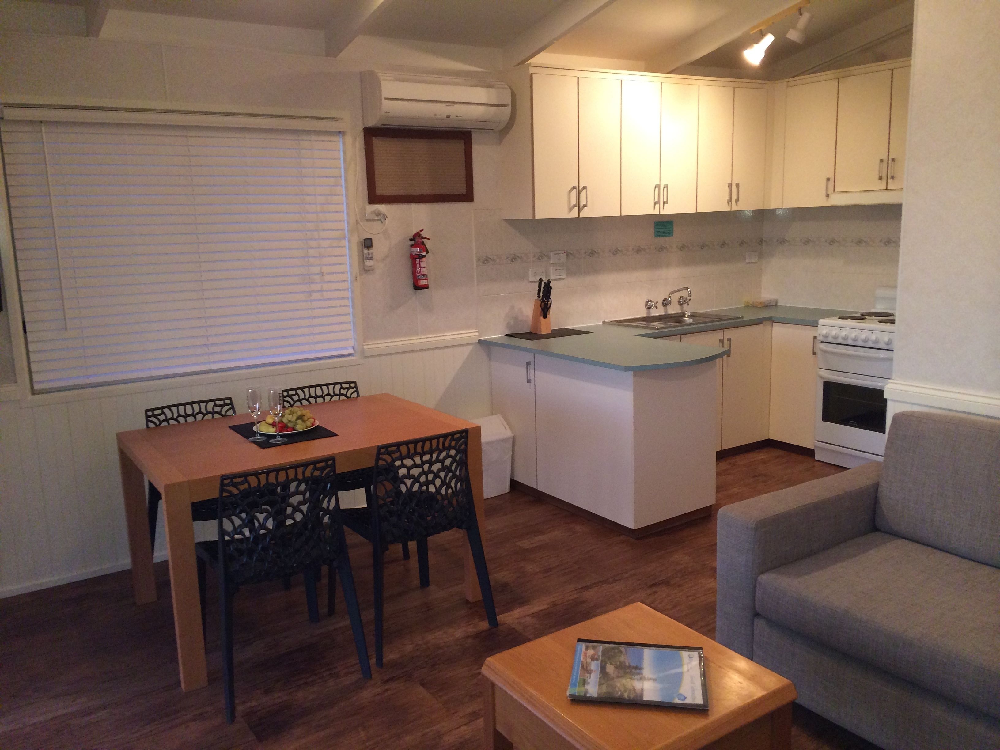 A compact kitchen with a dining area, a sofa, and a small table with a book.