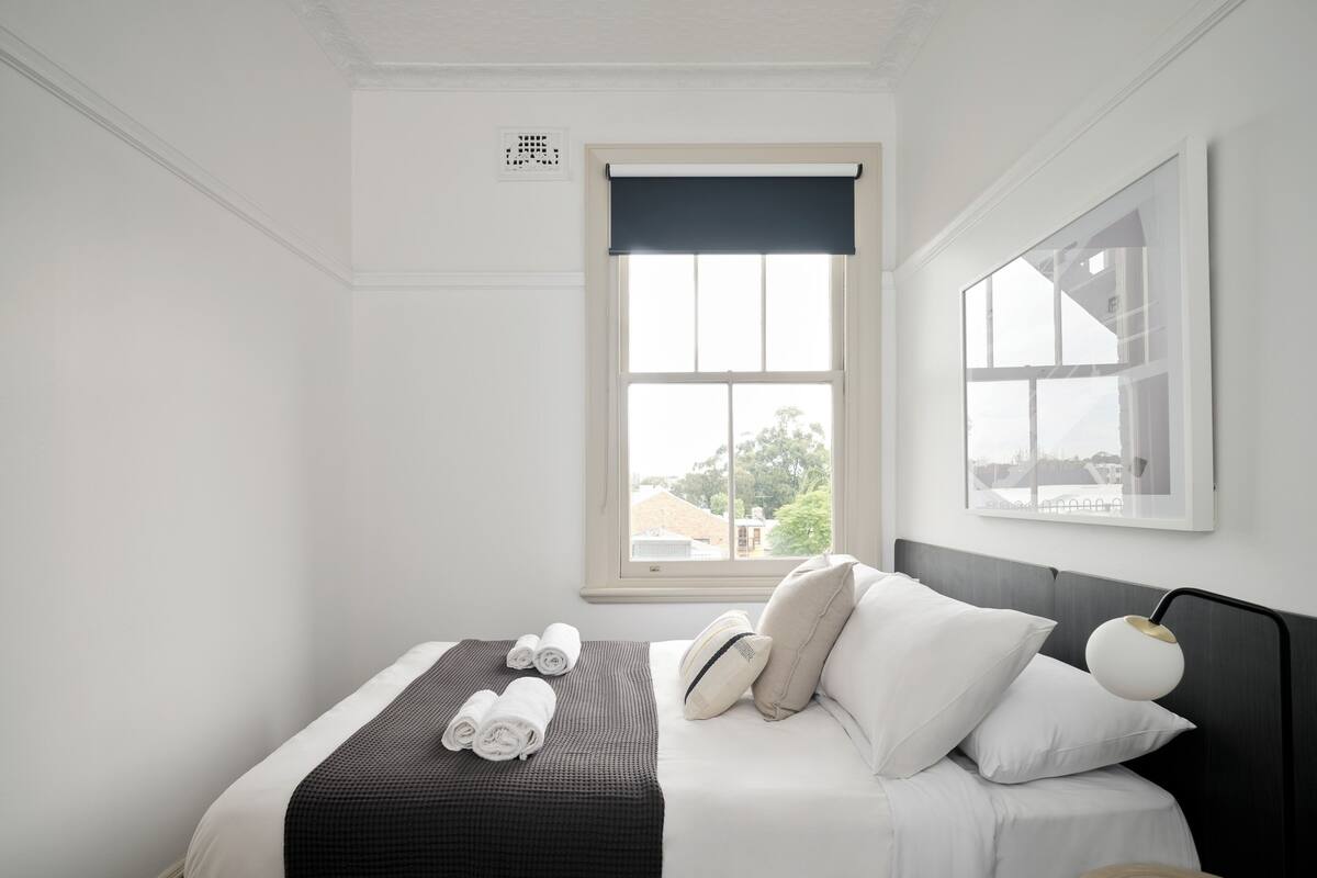 A hotel room with a bed, a window, and a view of the outside.
