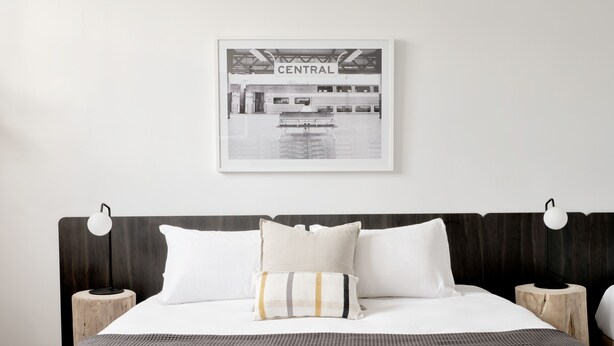 A bedroom with a bed, two bedside tables, a headboard, and a framed picture on the wall. - The Dunkirk Hotel (Pyrmont)