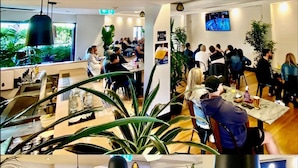 A modern restaurant with indoor seating, large windows, and potted plants. - The Dunkirk Hotel (Pyrmont)