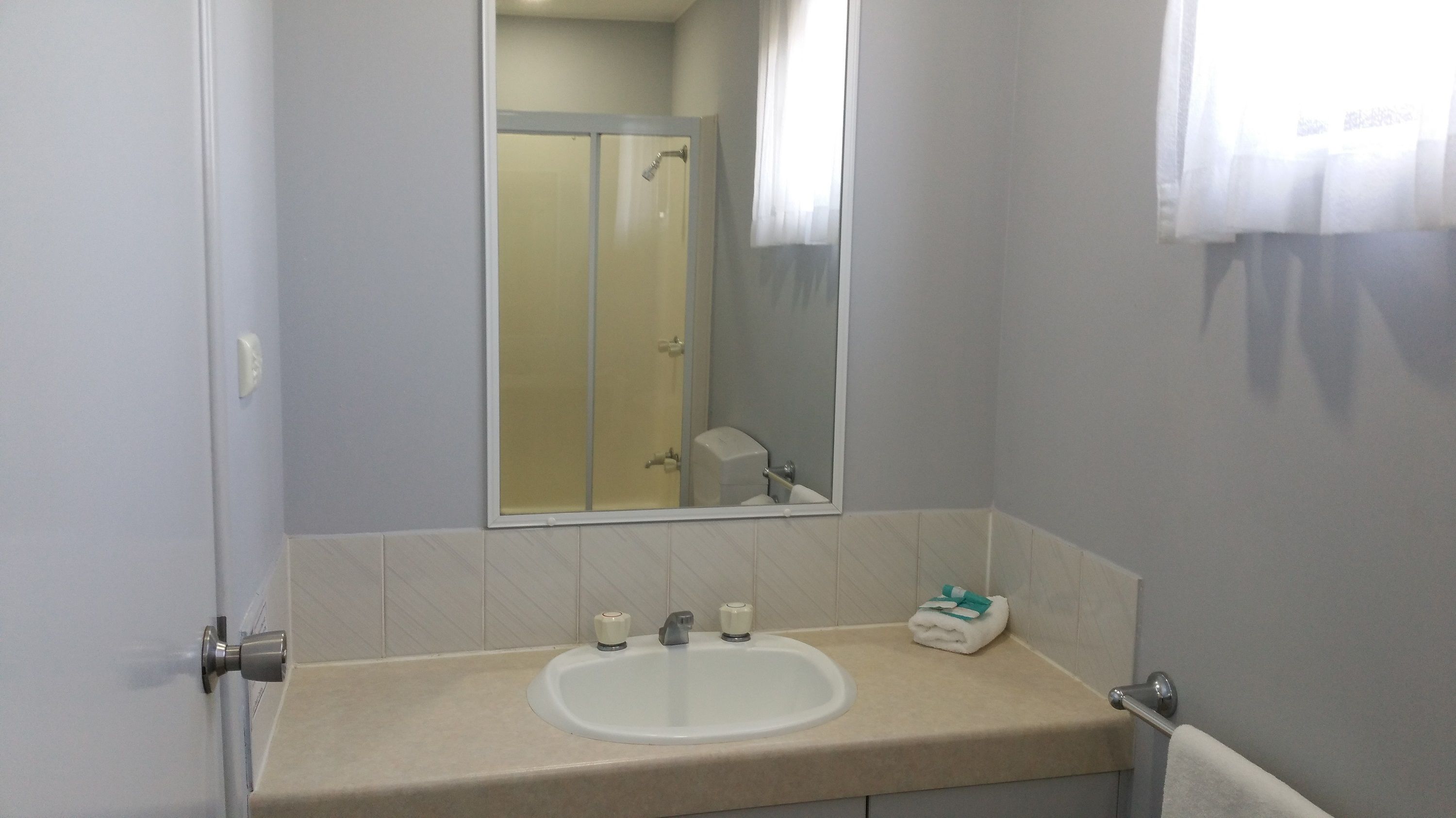 A bathroom with a sink, mirror, and shower.