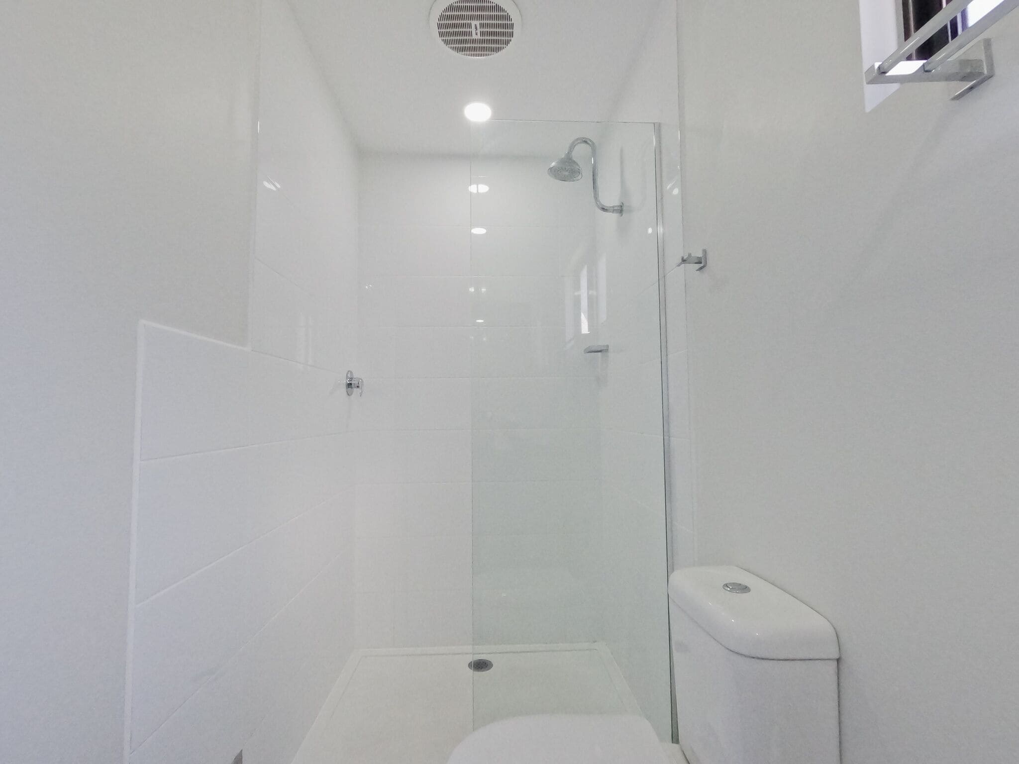A modern bathroom with a glass shower enclosure, a toilet, and a sink.