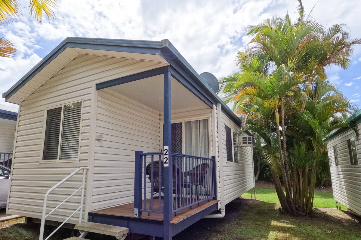 A mobile home with a porch, a small deck, and a number '22' sign.