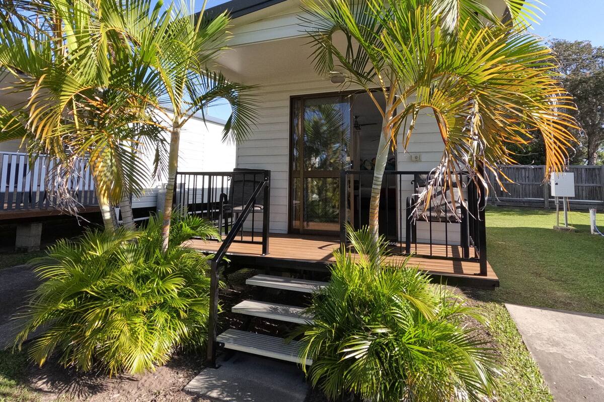A modern house with a covered porch, outdoor seating, and lush greenery.