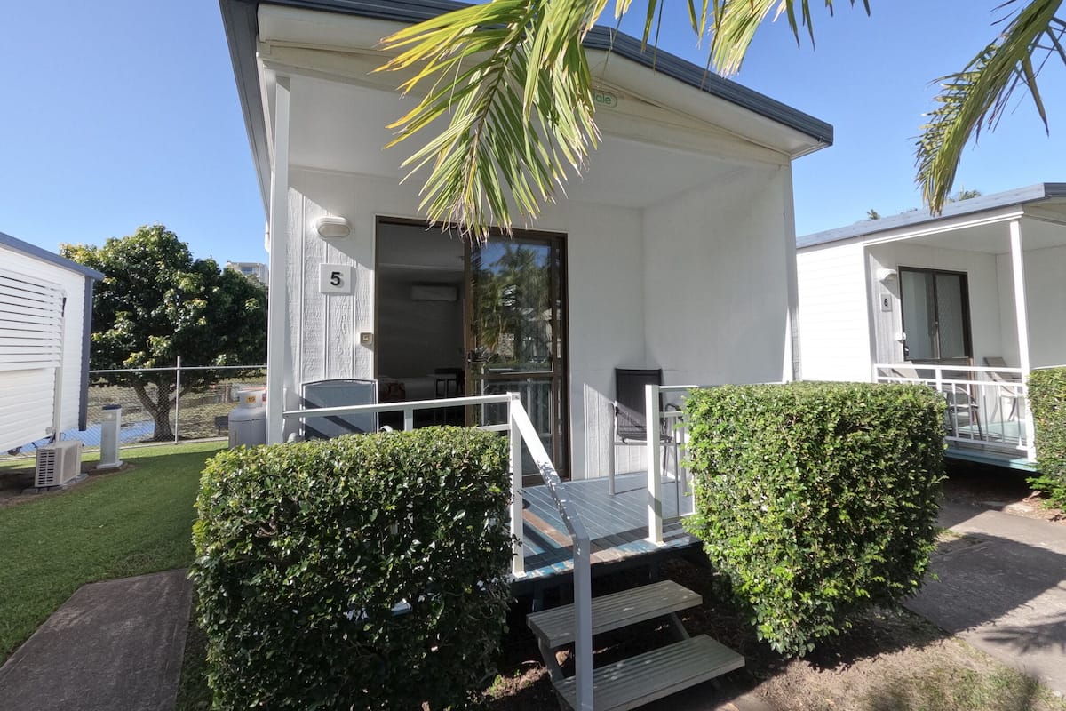 A modern, single-story building with a flat roof and a covered porch. It features a large glass door and a small set of stairs leading to the entrance.