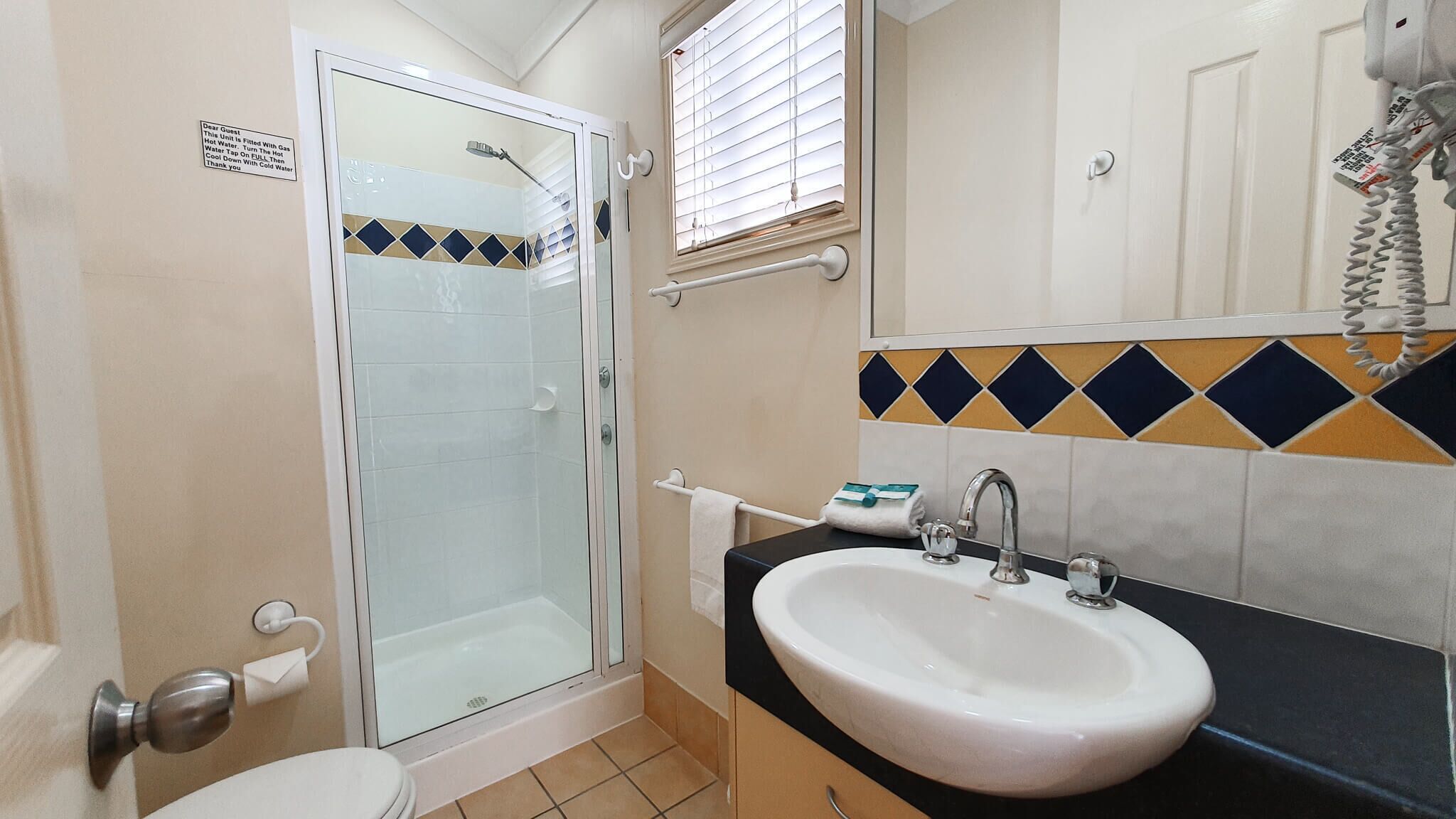 A bathroom with a glass-enclosed shower, a white sink, and a tiled backsplash.