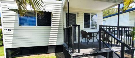 A mobile home with a porch, a small table, and a chair.
