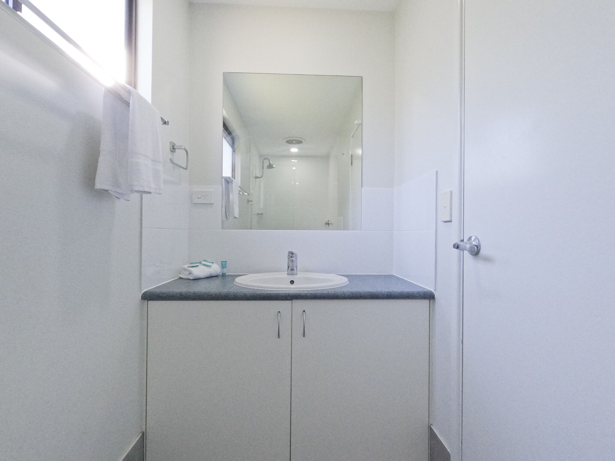 A bathroom with a white sink, a mirror, and a towel hanging on the wall.